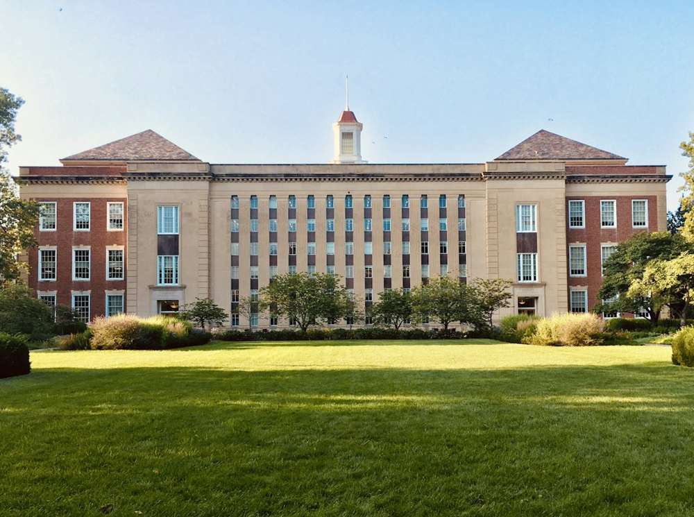 Red-brick university building across a green lawn