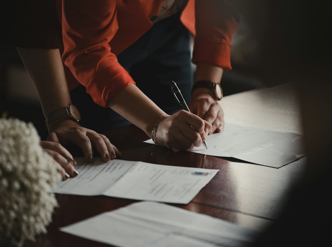 Two people signing paperwork at a table