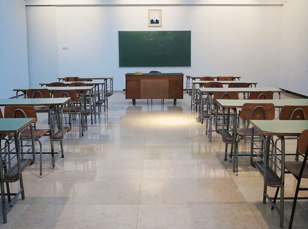 An empty classroom with rows of desks and a chalkboard